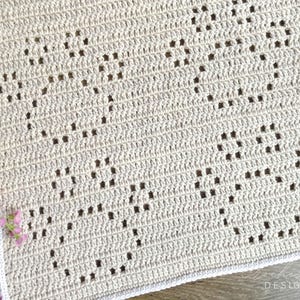 May include: A beige crochet blanket with a white border and a repeating diamond pattern.