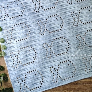 May include: A light blue crocheted baby blanket with a repeating square pattern.