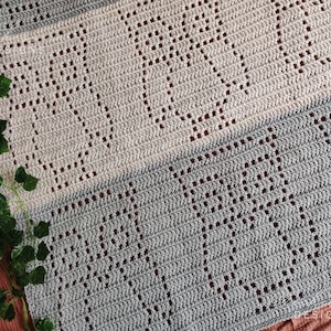 May include: A crochet blanket featuring a repeating owl pattern created with openwork stitches. The blanket is divided into horizontal sections of light beige and medium gray yarn, showcasing a textured design with visible owl silhouettes.