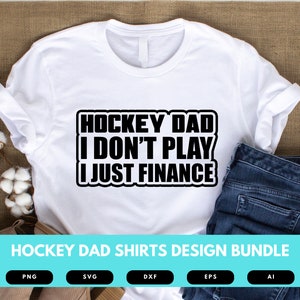 May include: White t-shirt with black text that reads "Hockey Dad I Don't Play I Just Finance". The shirt is on a brown burlap background with a pair of jeans and cotton balls.