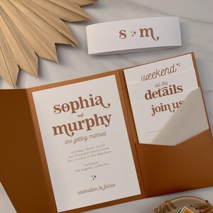 May include: A folded wedding invitation with a brown outer layer and a white inner layer. The invitation features the text "sophia and murphy are getting married" in a brown font. The invitation also includes the date and time of the wedding, as well as the location. The text "weekend: all the details join us" is on the inner layer of the invitation.