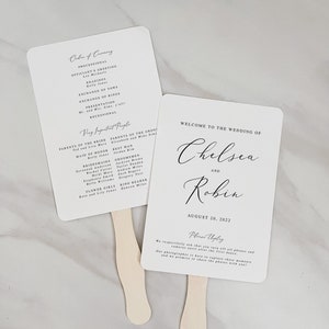 Puede incluir: Dos abanicos de boda blancos con texto en caligrafía negra. El abanico superior enumera el orden de la ceremonia y las personas importantes. El abanico inferior dice "Bienvenido a la boda de Chelsea y Robin, 20 de agosto de 2022". También dice "Desconecta" y pide a los invitados que apaguen sus teléfonos y cámaras hasta después del primer baile.