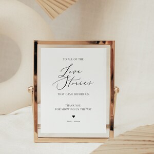May include: A white sign in a gold frame with the text "To all of the Love Stories that came before us. Thank you for showing us the way." and the names "Heidi & Andrew" at the bottom.