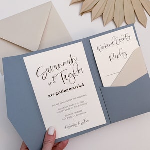 Könnte beinhalten: Eine blaue und weiße Hochzeitseinladung mit den Namen Savannah und Taylor und dem Text "are getting married". Die Einladung enthält das Datum und die Uhrzeit der Hochzeit, den Ort und den Text "Festivities to follow".