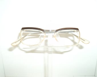 May include: A pair of clear plastic eyeglasses with brown accents on the top of the frames.