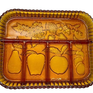 Könnte beinhalten: Serviertablett aus bernsteinfarbenem Glas mit vier geteilten Abschnitten. Das Tablett zeigt ein erhabenes Design von Früchten, darunter Birnen, Äpfel und Trauben.
