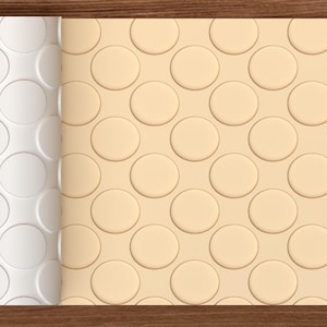 Op de afbeelding: Een rol lichtbeige textuurmateriaal met een herhalend patroon van verhoogde cirkels. De linkerkant van de rol is wit en toont het reliëf cirkelontwerp, terwijl de rechterkant hetzelfde patroon in een effen lichtbeige kleur weergeeft.