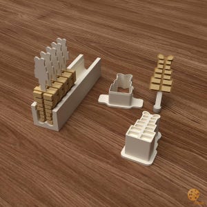 Op de afbeelding: Een set witte plastic koekjesvormers met een bijpassend wit opbergbakje. De vormers hebben een getrapte, rechthoekige vorm met een klein handvat. Verschillende lichtbruine koekjesvormen staan rechtop in het bakje als eindresultaat.