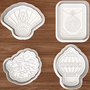May include: A set of four white plastic cookie cutters featuring embossed designs of a folding fan with a flower, a rectangular envelope with a circular emblem, a dragon head, and a traditional lantern with decorative patterns and tassels.