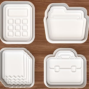 Puede incluir: Un juego de cuatro cortadores de galletas de plástico blanco con formas de oficina: una calculadora, una carpeta, una pila de papeles con borde inferior dentado y un maletín con asa y dos cierres, todos con detalles interiores en relieve.