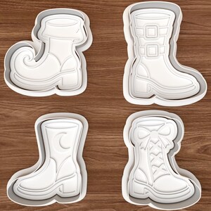 Könnte beinhalten: Ein Set aus vier weißen Kunststoff-Ausstechformen in Form verschiedener Stiefel. Die Designs umfassen einen Stiefel mit gekrümmter Spitze, einen hohen Schnallenstiefel, einen Stiefel mit Mondsichel-Detail und einen Schnürstiefel mit einer Schleife.