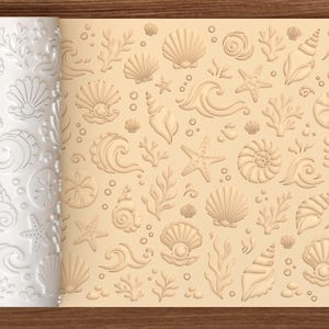 May include: A white cylindrical rolling pin featuring a raised, embossed pattern of various seashells, starfish, coral, and ocean waves. The design is shown imprinted into a light beige surface, displaying the repeating nautical motif clearly.