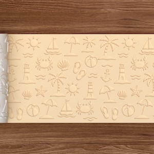 May include: A white rolling pin with a beach-themed pattern, including sailboats, palm trees, and seashells. The pattern is embossed on a light tan surface, perfect for creating summer-themed cookies or pastries.