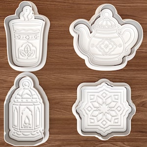 May include: A set of four white plastic cookie cutters featuring detailed embossed designs of a steaming glass of tea, a teapot, a decorative lantern, and an eight-pointed geometric star pattern with intricate lines and shapes.