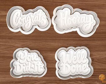 May include: Four white plastic cookie cutters with rounded, cloud-like borders. Each cutter features embossed script text: "Congrats", "Hooray", "You Did It", and "Well Done". The cutters have a raised edge design for creating detailed impressions.
