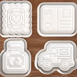 Puede incluir: Cuatro cortadores de galletas de plástico blanco con temática postal: un sello cuadrado con un corazón, una postal rectangular con un corazón, un tintero con una pluma estilográfica y un camión de reparto de correo con un icono de sobre.