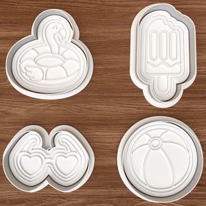 May include: A set of four white plastic cookie cutters featuring summer-themed shapes: a flamingo pool float, a popsicle with a bite taken out, heart-shaped sunglasses, and a round beach ball with segmented panels and a center circle.