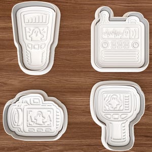 以下が含まれることがあります： ゴーストハンティング機器の形をした4つの白いプラスチック製クッキーカッターのセット。ハンドヘルドスキャナー、トランシーバー、ビデオカメラ、サーマルイメージングカメラが含まれており、それぞれのディスプレイ画面にはゴーストのアイコンが浮き彫りにされています。