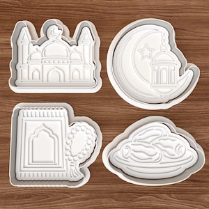 Peut inclure: Quatre emporte-pièces en plastique blanc de différentes formes. L'un est une mosquée, un autre un croissant de lune avec une étoile et une lanterne, un troisième un tapis de prière avec des perles et le dernier une assiette de dattes.