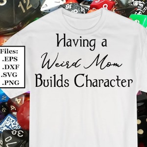 Peut inclure: T-shirt blanc avec un texte noir qui dit "Avoir une mère bizarre construit le caractère". Le t-shirt est entouré de dés colorés.