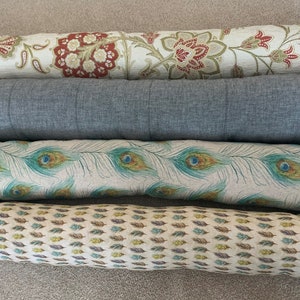 Puede incluir: Cuatro almohadas de apoyo decorativas con diferentes patrones. La almohada superior tiene un patrón floral en tonos beige, marrón y rojo. La segunda almohada es de color gris sólido. La tercera almohada tiene un patrón de plumas de pavo real en tonos de verde, beige y marrón. La almohada inferior tiene un patrón de plumas en tonos de beige, marrón y verde.