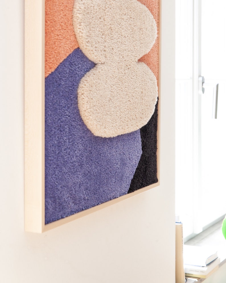 May include: A framed abstract wall art piece with a textured, fuzzy surface. The artwork features a combination of peach, purple, black, and white colors.