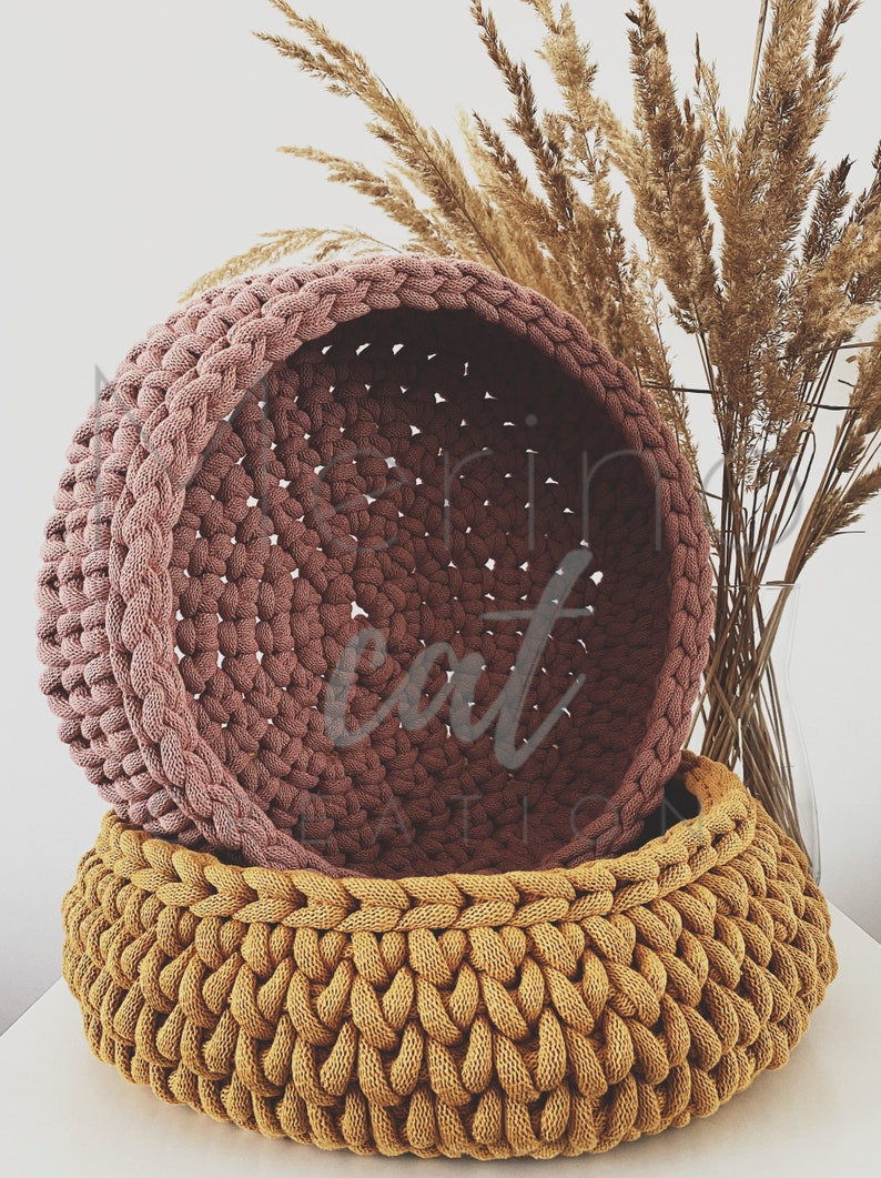 Puede incluir: Dos cestas de crochet, una de color rosa polvoriento y otra de color amarillo mostaza. Las cestas est&aacute;n apiladas una encima de la otra.