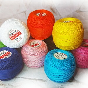 May include: Assortment of colorful yarn balls, each with a label indicating the brand "Arraduci" and "Atlaser 30". The yarn balls are in shades of white, orange, yellow, pink, blue, and green.
