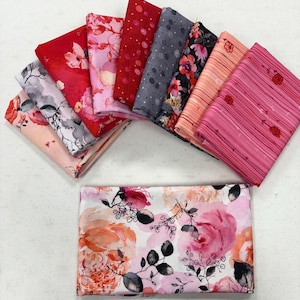 May include: An assortment of folded fabric pieces in various floral patterns and colors. The fabrics include shades of red, pink, gray, and peach, with designs featuring flowers and polka dots. One larger piece of fabric with a large floral pattern is also visible.