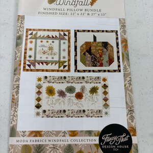 May include: A Windfall Pillow Bundle with a finished size of 22" x 22" & 27" x 15". The cover features three quilt designs with pumpkins and sunflowers. The text "Windfall" and "Fancy That Design House & Co" are also visible.