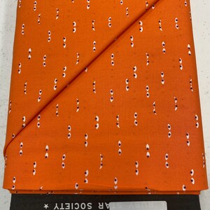 May include: Orange fabric with a white eye pattern. The fabric is folded in half and the label reads "RS5120 116 Tiny Frights Pumpkin Quilting Divas Sewing Boutique RUBY STAR SOCIETY★"