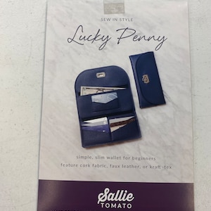 May include: A sewing pattern for a wallet called "Lucky Penny" by Sallie Tomato. The pattern features a blue wallet with multiple pockets and a flap closure. The text "Sew in Style" is at the top of the pattern.