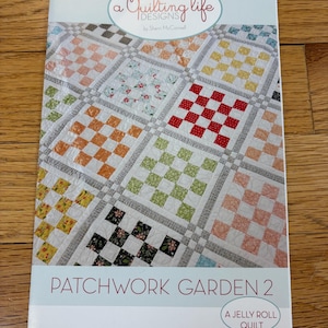 Peut inclure: Une brochure de modèle de courtepointe intitulée "Patchwork Garden 2" par Shem McConnell. La couverture présente une courtepointe patchwork colorée avec un motif en damier dans différentes couleurs, notamment le rouge, le vert, le jaune et le bleu.