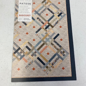 May include: A sewing pattern for a quilt called "Baker's Lattice" by BasicGrey for Moda. The pattern features a geometric design with a mix of blue, brown, orange, and yellow fabrics.