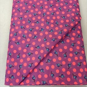 May include: Pink fabric with a repeating pattern of small blue flowers and large pink polka dots.