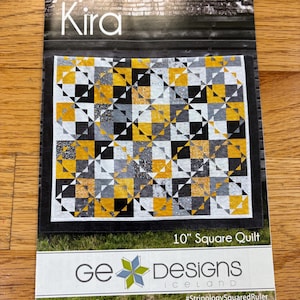 May include: A quilt pattern named "Kira" featuring a geometric design in black, white, grey, and yellow. The pattern is for a 25.4 cm square quilt. The package also indicates a Queen size quilt of 246.4 cm x 289.6 cm. The brand is Ge Designs Iceland.