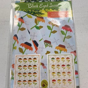 May include: Black Eyed Susan quilt pattern by Fig Tree & Co. featuring a simple piecing technique. The pattern includes a sample quilt layout with black-eyed Susan flowers in shades of orange, yellow, and green on a white background.