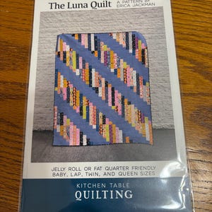 May include: A quilting pattern for "The Luna Quilt" by Erica Jackman. The pattern is for a jelly roll or fat quarter friendly quilt and includes sizes for baby, lap, twin, and queen. The pattern is for kitchen table quilting.