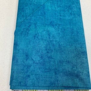 May include: A teal blue fabric with a subtle grid pattern. The fabric is folded and the edge of the fabric has the text "ROBERT ALLEN" printed on it.