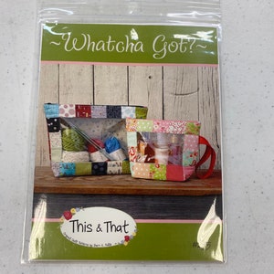 May include: A sewing pattern for a clear zippered pouch with a patchwork design. The pattern is titled "Whatcha Got?" and "This & That" with the text "Original Quilt Patterns by Terri C. Falls".