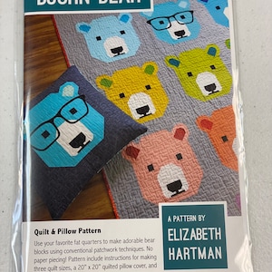 May include: A quilt and pillow pattern featuring a cute bear design with glasses. The pattern is by Elizabeth Hartman and includes instructions for making three quilt sizes and a 20" x 20" quilted pillow cover.