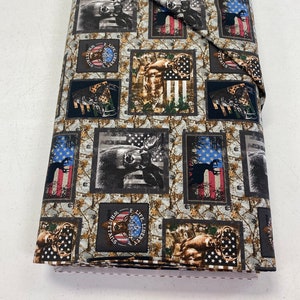 May include: Rolled fabric with a repeating pattern of deer, American flags, and the text "White Tails Pursuit of Life Liberty". The design incorporates camouflage and patriotic elements in shades of brown, grey, black, white, red, and blue.