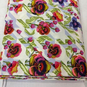 May include: A white fabric with a blue and white geometric pattern and a floral print of pink, yellow, green, and purple pansies.