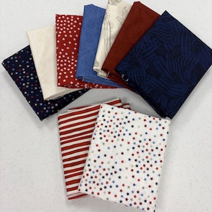 May include: A collection of folded fabric squares in various patriotic patterns. Designs include red and white stripes, white with red, white, and blue stars, and navy blue with white stars. Other fabrics feature topographic and abstract designs.