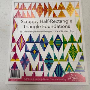 May include: A white paper foundation featuring a variety of colourful geometric patterns. The text reads "Scrappy Half-Rectangle Triangle Foundations" with "25 Different Paper-Pieced Designs - 7.6cm x 15.2cm Finished Size". The paper includes a barcode and the text "100 Scrap-Busting Paper Foundations by Leila Gardunia".