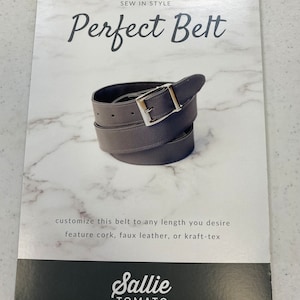 May include: A gray leather belt with a silver buckle. The packaging says "Sew in Style Perfect Belt" and "Sallie Tomato Your Source for Quality Sewing Patterns & Purse Supplies".