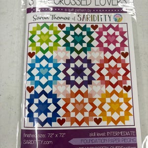 May include: A Star Crossed Lovers quilt pattern by Sarah Thomas of Sariditty in a clear plastic sleeve. The cover features a colorful grid of nine star blocks with heart centers in various hues. Finished size is 72 inches by 72 inches.