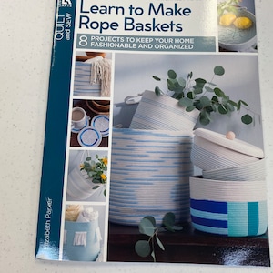 May include: Book cover with the title "Learn to Make Rope Baskets" and a subtitle "8 Projects to Keep Your Home Fashionable and Organized". The cover features various rope baskets in blue and white stripes, with some baskets featuring additional colors like turquoise and yellow.