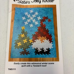 May include: A printed pattern for a Jolly Twister quilt by Twister Sisters. The quilt design features a Christmas tree and a gnome on a blue background. The text reads, "Easily create this whimsical winter scene quilt with a Twister tool!"