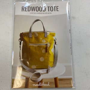 May include: A sewing pattern for a yellow tote bag with white polka dots. The pattern is called "Redwood Tote" and is a mid-size crossbody tote with a zip top. The pattern is from Noodlehead.